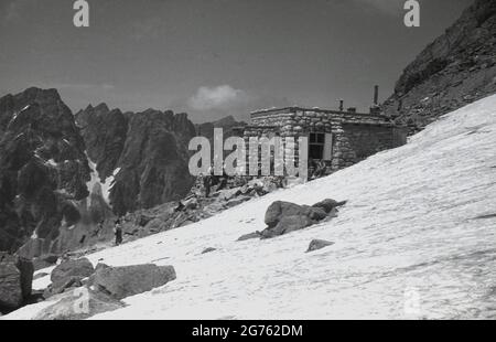 1935, storici, escursionisti che si trovano fuori di un rifugio in pietra costruito sulle montagne Sudeten, Cecoslovacchia. Tali edifici forniva rifugio e rifugio a escursionisti ed escursionisti, quando camminavano sulla catena montuosa dei Sudeti, che il territorio Sudetenland - annesso dalla Germania nel 1938 - prende il nome. Formano il punto più alto del massiccio boemo, un certo numero di catene montuose che coprono grandi parti dell'Europa Cemtral. Foto Stock