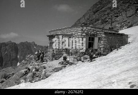 1935, storici, escursionisti che si trovano fuori di un rifugio in pietra costruito sulle montagne Sudeten, Cecoslovacchia. Tali edifici forniva rifugio e rifugio a escursionisti ed escursionisti, quando camminavano sulla catena montuosa dei Sudeti, che il territorio Sudetenland - annesso dalla Germania nel 1938 - prende il nome. Formano il punto più alto del massiccio boemo, un certo numero di catene montuose che coprono grandi parti dell'Europa Cemtral. Foto Stock