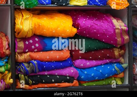 Tradizionale Rajasthan vestiti i materiali per la vendita in un negozio mercantile di stoffa in India. Colorato Jodhpur strada stalla di tessuto. Bandhej o Bandhani ampiamente uso Foto Stock