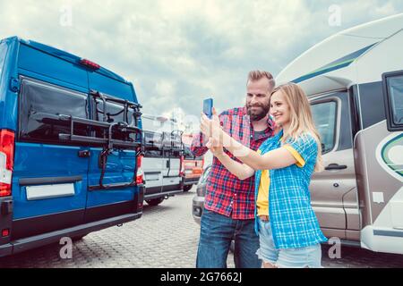 Donna e uomo che prendono selfie di fronte a RV o camper in attesa Foto Stock