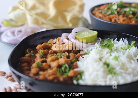 Fagioli rossi in un sugo denso e piccante di cipolle e pomodori serviti con riso basmati e papà al vapore. Comunemente noto come rajma masala an Foto Stock