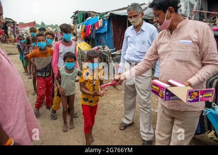 Nuova Delhi, India. 11 Luglio 2021. I volontari del Bhartiya Janta party distribuiscono cioccolatini e facemask ai bambini di baraccopoli a New Usmanpur durante la campagna di sensibilizzazione Covid-19. Hanno anche informato i bambini circa le misure di Covid-19. Le autorità governative e sanitarie prevedono che i bambini saranno maggiormente colpiti dalla terza ondata in India. (Foto di Pradeep Gaur/SOPA Images/Sipa USA) Credit: Sipa USA/Alamy Live News Foto Stock