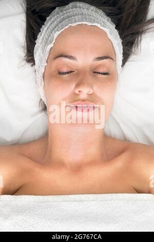 Giovane donna che posa gli occhi chiusi, ottenendo trattamento di bellezza facciale, vista dall'alto. Foto di alta qualità Foto Stock