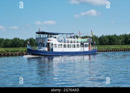 Amersfoort, Hoogland, Paesi Bassi 13 giugno 2021, Bicyboat, traghetto eemland sul fiume EEM con passeggeri e una diga e cielo blu nel Foto Stock