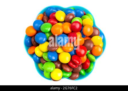 Bottoni di cioccolato color arcobaleno rivestiti con caramelle in una ciotola blu divertente su sfondo bianco Foto Stock