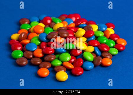 Una pila di bottoni di cioccolato color arcobaleno con rivestimento di caramelle Foto Stock