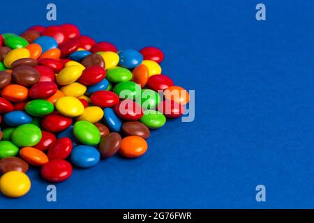 Una pila di bottoni di cioccolato color arcobaleno con rivestimento di caramelle Foto Stock