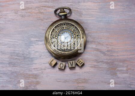 Una vista dall'alto di un orologio da tasca vintage e piastrelle che scrivono "amore" Foto Stock