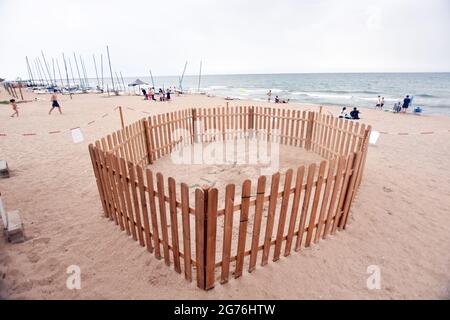 Vista di un nido di sabbia recintato dove la tartaruga di testa di loggera ha generato le sue uova alla spiaggia di Calafell.UNA tartaruga di testa di loggerhead (Caretta caretta), in grave pericolo di estinzione, è arrivato alla spiaggia di Calafell il 19 giugno per deporre 161 uova in un nido fatto nella sabbia. La polizia locale di Calafell ha preso 61 delle uova al CRAM (Centro per la conservazione e il recupero degli animali marini) A causa della necessità di un incubatore e il resto delle uova nel nido sono custodite 24 ore fino a quando non si schiudono dal Gruppo per lo studio e la protezione degli ecosistemi catalani - ecologi della Catalogna (GEPEC-EDC) durante i due mesi o Foto Stock