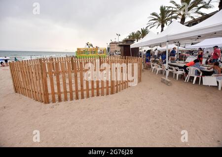 Vista di un nido di sabbia recintato dove la tartaruga ha generato le sue uova vicino alla tenda dove i volontari monitorano il nido.UNA tartaruga di testa di loggerhead (Caretta caretta), in grave pericolo di estinzione, è arrivato alla spiaggia di Calafell il 19 giugno per posare 161 uova in un nido fatto nella sabbia. La polizia locale di Calafell ha preso 61 delle uova al CRAM (Centro per la conservazione e il recupero degli animali marini) A causa della necessità di un incubatore e il resto delle uova nel nido sono custodite 24 ore fino a quando non si schiudono dal Gruppo per lo Studio e la protezione degli ecosistemi catalani - ecologi della Catalogna Foto Stock