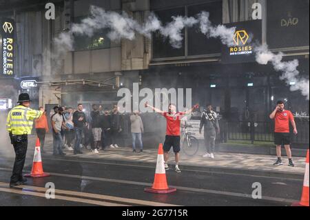 Broad Street, Birmingham 11 luglio 2021 i tifosi si sono scontrati l'uno con l'altro dopo che l'Inghilterra si è schiantata fuori dalla finale Euro 2020 con l'Italia che ha vinto a pene, rendendolo 56 anni di ferimento. I fan si sono rovesciati fuori dei pub e dei bar su Broad Street nel centro di Birmingham, mentre la polizia ha formato linee. Molti fan sembravano infeludati, una donna sembrava perduta mentre camminava attraverso le fontane. Una granata di fumo è stata lanciata anche mentre la polizia ha cercato di calmare i sostenitori, anche se un kit inglese con un ventilatore ha fatto sventolare una bottiglia di vodka in aria prima che la polizia minacciasse di usare il gas se non lo ha fatto cadere. L'uomo è stato poi arrestato. Foto Stock