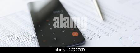 Telefono cellulare con calcolatrice su documenti closeup Foto Stock