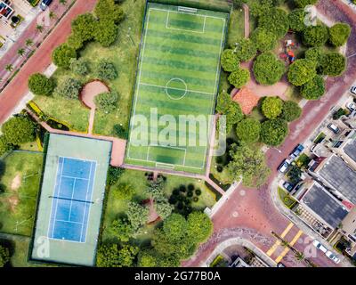 Tiro drone diretto di campo da calcetto vuoto e campo tenis circondato da parco e alberi in una comunità recintata fuori Guayaquil City, Ecuador. Foto Stock