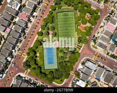 Tiro drone diretto di campo da calcetto vuoto e campo tenis circondato da parco e alberi in una comunità recintata fuori Guayaquil City, Ecuador. Foto Stock