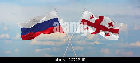Bandiere della Russia e della Georgia che sventolano nel vento su flagpoli contro il cielo con le nuvole nel giorno di sole. Simboleggiando la relazione, il dialogo tra due contri Foto Stock