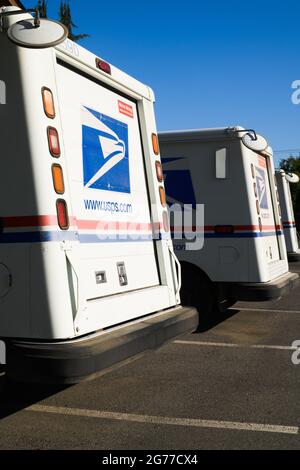 Garofano, WA, USA - 11 luglio 2021; UNA fila di piccoli furgoni del servizio postale USPS sotto il sole sotto un cielo blu Foto Stock