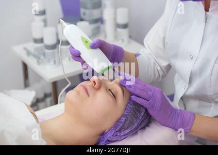 Salone di bellezza. Il cosmetologo effettua una procedura di peeling dell'acqua per il cliente. Vista laterale. Il concetto di cura professionale della pelle. Foto Stock