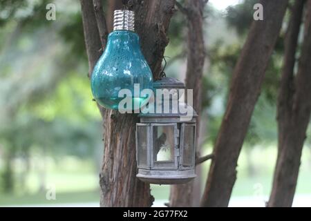 Lampadina blu e lanterna metallica appesa ad un albero Foto Stock