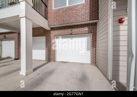 Tre porte per garage in sezione bianca di un edificio con mattoni Foto Stock