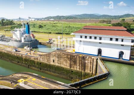 Un grande carico passò appena attraverso il canale di Panama in una giornata di sole. Si possono vedere gli uffici principali e una delle serrature. Foto Stock