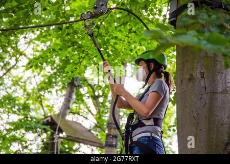 Eccessiva cautela, regolamentazione o abitudine? Donna con maschera FFP2 su un corso di arrampicata Foto Stock