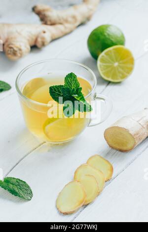 Tè verde con zenzero, menta e lime sul tavolo di legno bianco Foto Stock