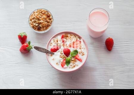 Colazione salutare. Yogurt con fragole e muesli in una ciotola sul tavolo. Vista dall'alto Foto Stock