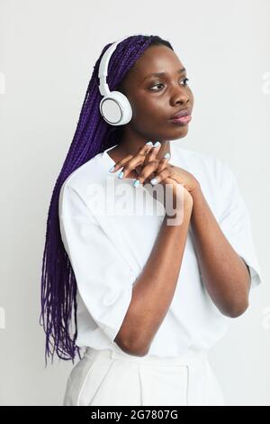 Ritratto minimo di una giovane donna afroamericana che indossa le cuffie su sfondo bianco Foto Stock