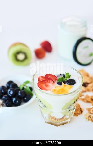 Bicchiere con delizioso dessert sano composto da yogurt, panifici e muesli sul tavolo Foto Stock