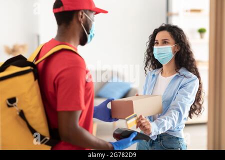 Uomo nero che tiene il cliente della macchina POS che paga con la carta di debito Foto Stock