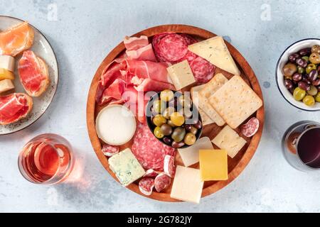 Salumi e formaggi con vino e olive, top shot. Panini, jamon, formaggio blu, bicchieri di rosa e vino rosso, una posa piatta Foto Stock