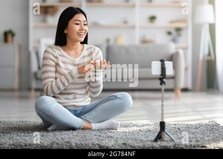 Blog video. Smiling Asian Blogger Lady registrazione Vlog a casa Foto Stock