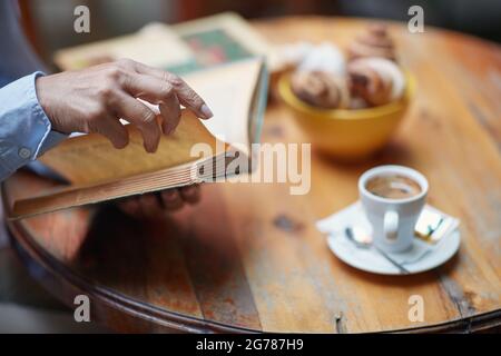 primo piano della mano di una donna anziana caucasica che tiene un libro, girando pagina Foto Stock