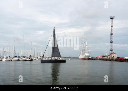 Stralsund, Germania. 23 Giugno 2021. Una barca a vela nera passa davanti al Gorch Fock 1 nel porto della città. Il tre-padrone serve come una nave del museo. Credit: Stefano Nosini/dpa-Zentralbild/ZB/dpa/Alamy Live News Foto Stock