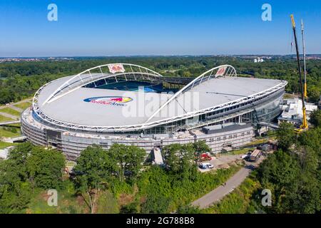 14 giugno 2021, Sassonia, Lipsia: Due gru si trovano alla Red Bull Arena. La casa di RB Leipzig è in fase di ricostruzione. La capacità dello spettatore aumenta da 42,558 a 47,069 in piedi e seduti. L'esterno dello stadio è chiuso con una facciata insonorizzata. L'argine dell'ex Zentralstadion, che comprende l'arena, è stato aperto dietro lo storico campanile per fare spazio ad un nuovo ingresso. RB Leipzig sta investendo nella conversione 60 milioni di euro entro il 2022. (Vista aerea con drone) Foto: Jan Woitas/dpa-Zentralbild/ZB - NOTA IMPORTANTE: In conformità con le norme di t Foto Stock