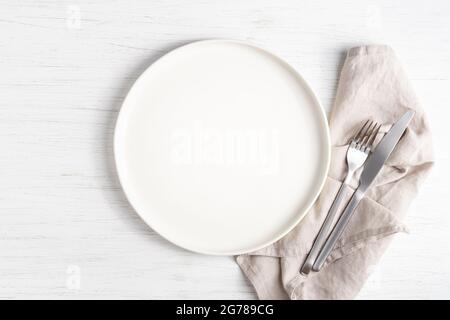 Piatto bianco vuoto e posate argentate su tovagliolo di lino. Foto Stock