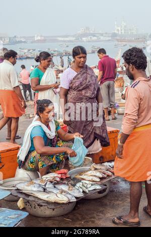 Le donne indiane commercianti di pesce che indossano saris colorati che vendono i loro prodotti al porto di Vizhinjam, Kerala, India Foto Stock