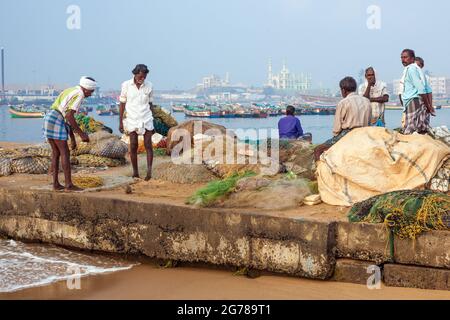 Gruppo di pescatori indiani che tende la loro rete sul lungomare a Vizhinjam, Kerala, India Foto Stock