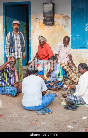 Gruppo di pescatori fuori servizio seduti a terra carte da gioco, Vizhinjam, Kerala, India Foto Stock