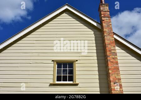 Muro particolare di casa in legno d'epoca con camino in mattoni rossi e tetto a tegole. Foto Stock