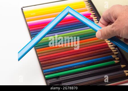 Mano, dita e gamma di colori; matite colorate, gamma completa; angoli colorati tenuti dalla mano dell'adulto Foto Stock