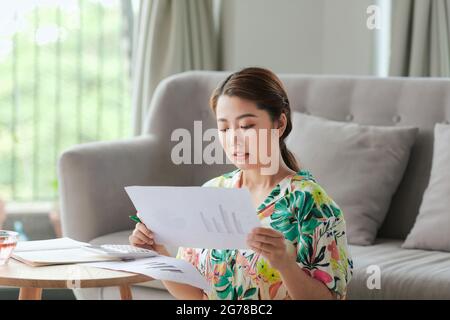 Ragazza studentesca felice che fa i compiti mentre si siede sul pavimento a casa Foto Stock