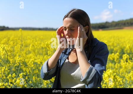 Donna stressata che soffre mal di testa in un campo giallo in estate Foto Stock