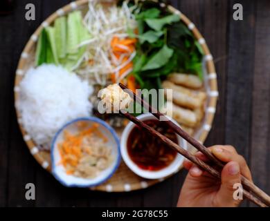 La gente tiene i chopsticks raccogliere i rotoli di primavera fritti su vassoio di cibo vegano vietnamita, il riso con panini, popolare cucina vietnamita Foto Stock