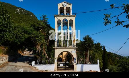 Isole IONIE, Ithaka, isola di Odysseus, Vathi, distretto di Perachori, Si trova su un pendio boscoso di montagna, chiesa a Perachori, filigrana campanile con orologio, cielo blu Foto Stock