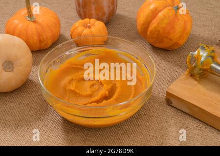 Purea di zucca tostata fatta in casa da zero. Purea fresca in una ciotola di vetro primo piano sul tavolo da cucina Foto Stock