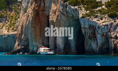 Isole IONIE, Zante, costa nord-orientale, Grotte Blu, Grotte Blu, la luce del mattino, costa rocciosa, piccola barca per escursioni è all'ancora Foto Stock