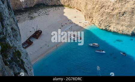 Zakynthos, Paralia Navagio, Shipwreck Beach, vista dall'alto nella baia e la spiaggia, relitto della MV Panagiotis, folla di persone sulla spiaggia, molte escursioni in barca all'ancora, acque turchesi Foto Stock