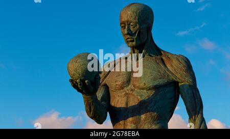 Zante, città di Zante, statua dell'anatomia di un uomo in memoria di Andreas Vesalius, il fondatore della medicina anatomica, morto a Zante nel 1564, la statua tiene un cranio in mano, cielo blu sullo sfondo, nuvole individuali Foto Stock