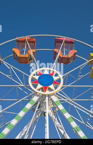 Ruota panoramica contro il cielo blu con colorate cabine vuote Foto Stock